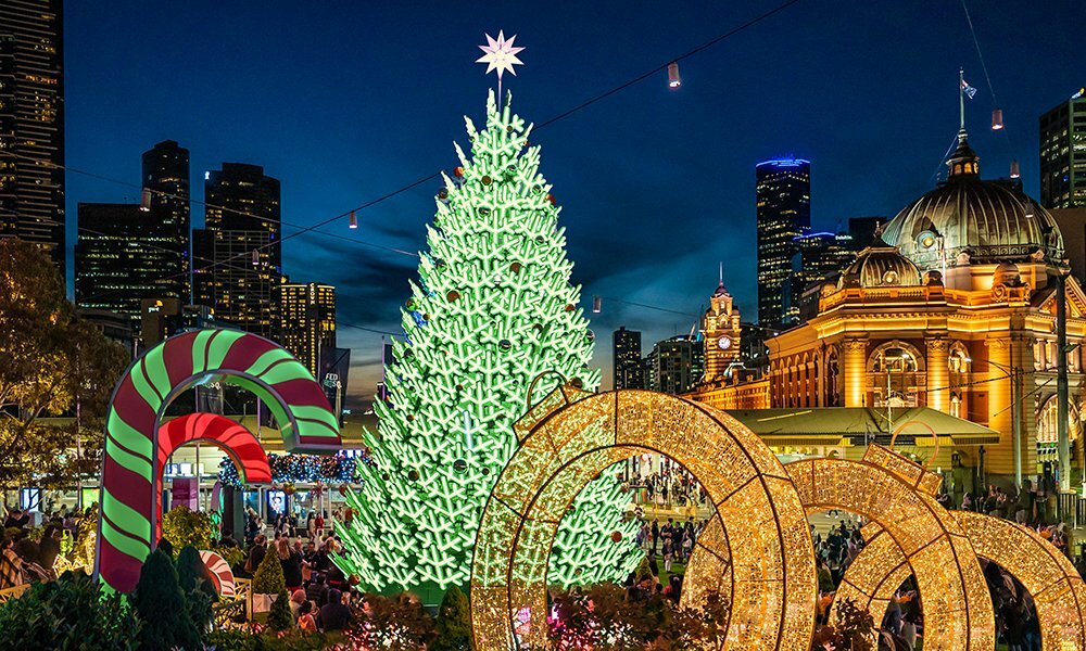 Christmas tree lit up at night with Flinders Street Station in the background.