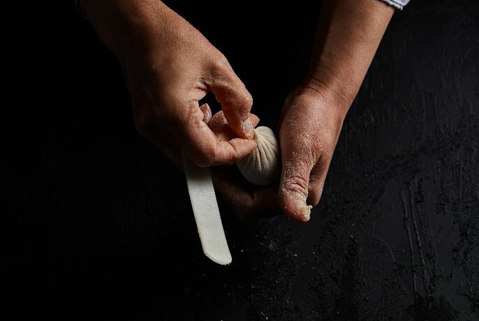 Chef twisting a dumpling between his fingers.
