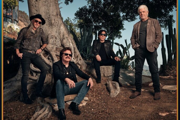 Members of The Doobie Brothers in a bush setting beside an old tree.