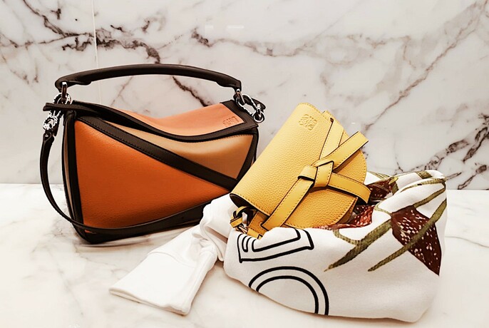 Brown and yellow handbags on a marble background with scarves.