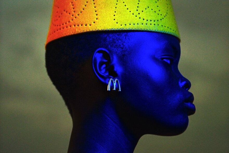 Profile portrait of an African woman with a rainbow-coloured hat.