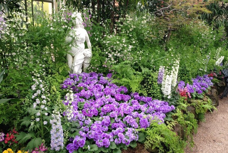 A statue surrounded by flower beds in Fitzroy Gardens