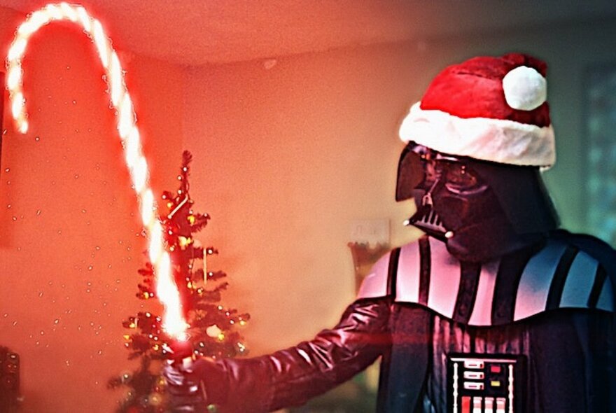 A Star Wars character wearing a Santa hat and holding a candy cane.
