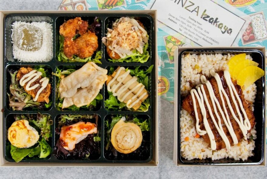 A nine-compartment bento box with chicken and fish, next to a takeaway fried chicken and rice dish.