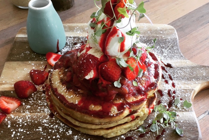 Stack of pancakes with berries and cream.