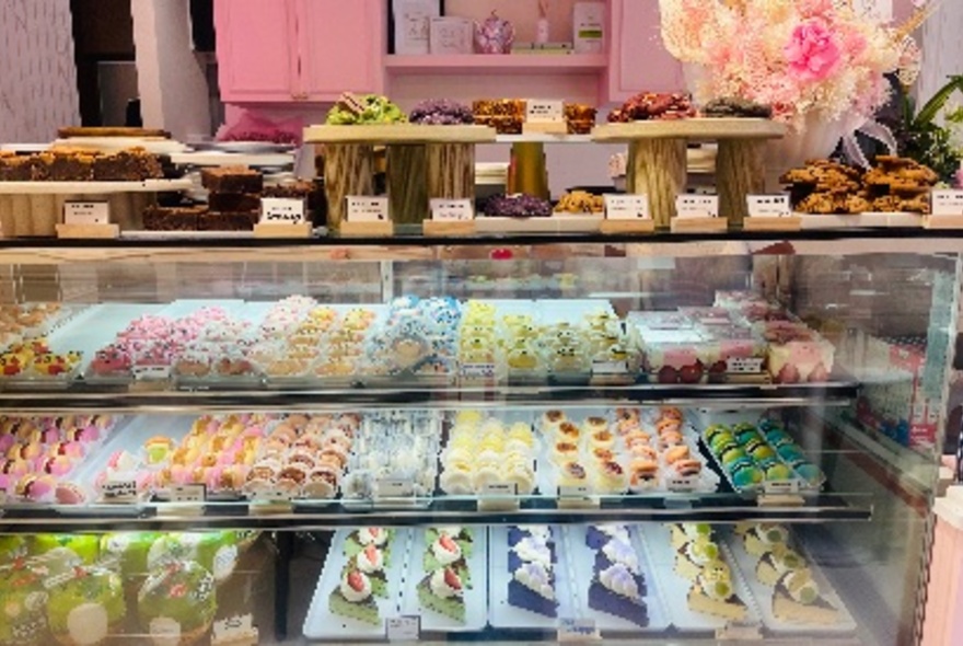 A cabinet full of small, delicious cakes in a pink shop. 