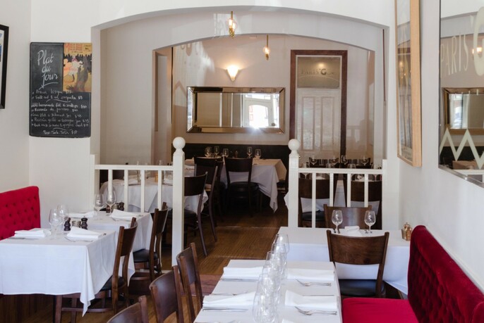 Split-level restaurant interior with white napery, banquette seating and balustrade.