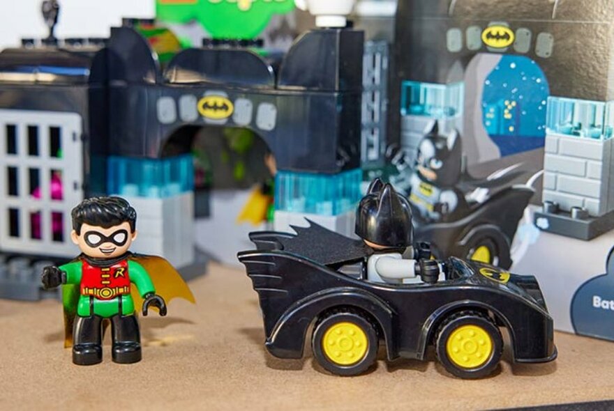 Lego figurines of Batman in the Batmobile and Robin beside it.