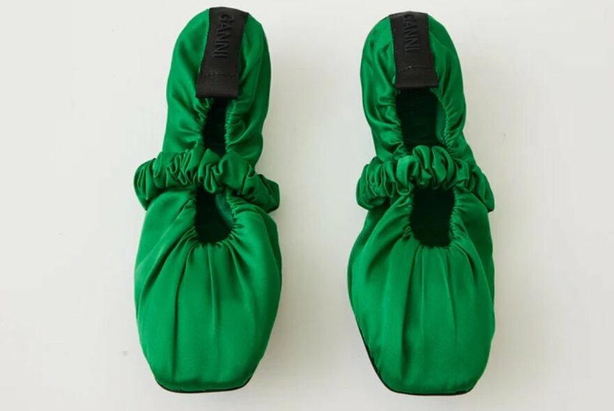 A pair of green ballet slides in silky fabric with scrunchie straps.