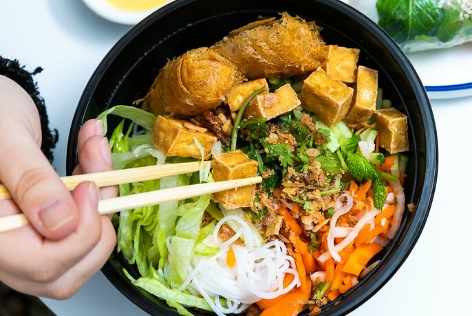 Bowl of tofu, spring rolls, noodles and vegetables.