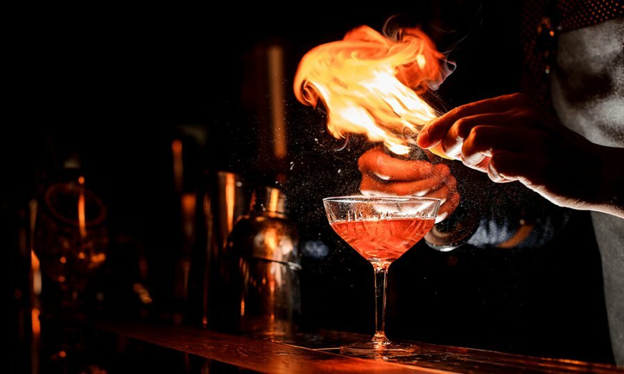 Fire blowing over a cocktail at a bar