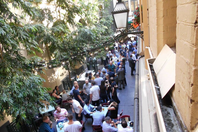 Looking down from upper storey of Mitre Tavern to view of people sitting and standing in laneway.