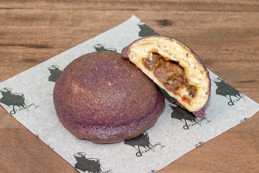 A meat-filled steamed bun, resting on a paper napkin.