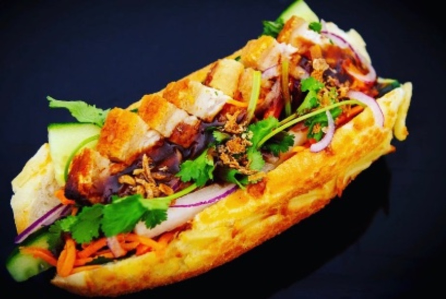 A banh mi - a bread roll filled with crispy pork and salad ingredients.