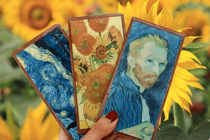 Van Gogh-like illustrations in three chocolate blocks, being held in someone's hand.