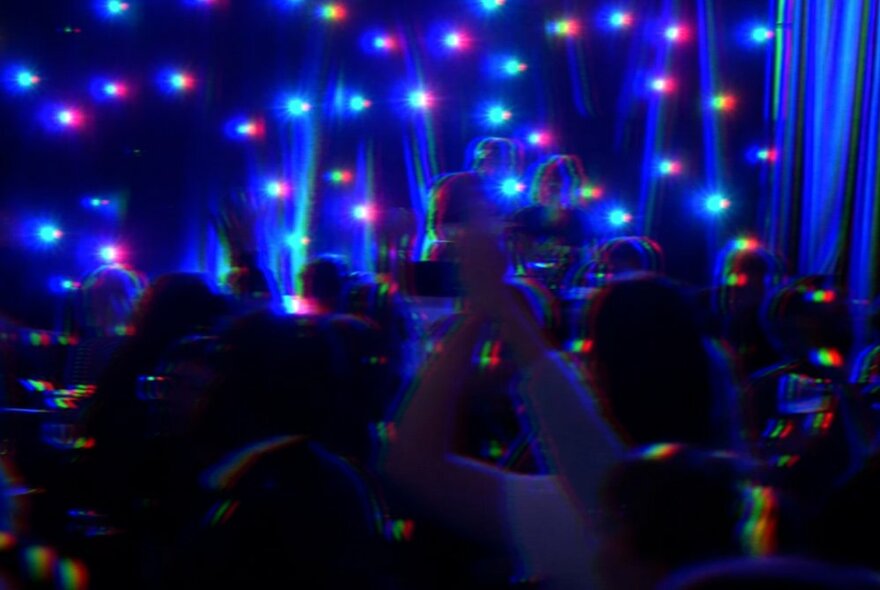Blurry picture of blue strobe lights and people dancing.