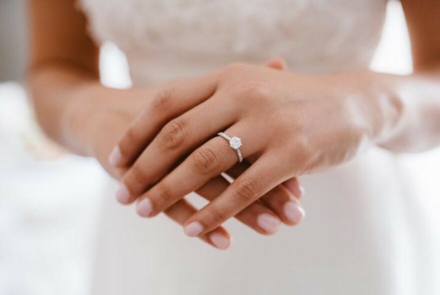 Woman in white wearing a diamond ring.