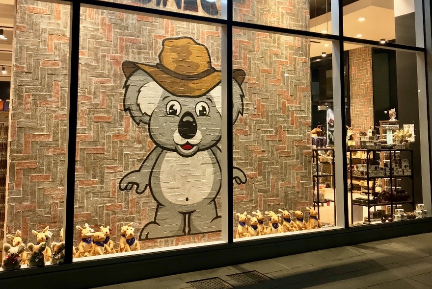 Shop window display featuring a large wall hanging of a cartoon koala.