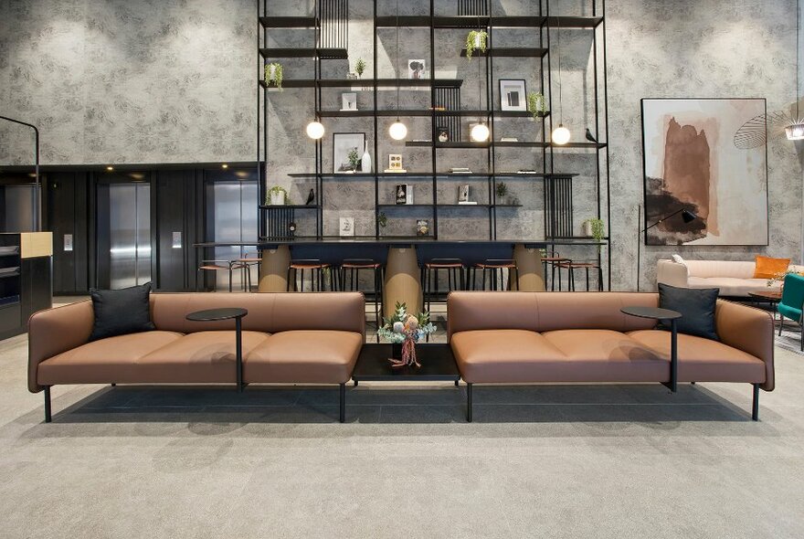Hotel foyer with grey walls with black shelves and brown low seating.