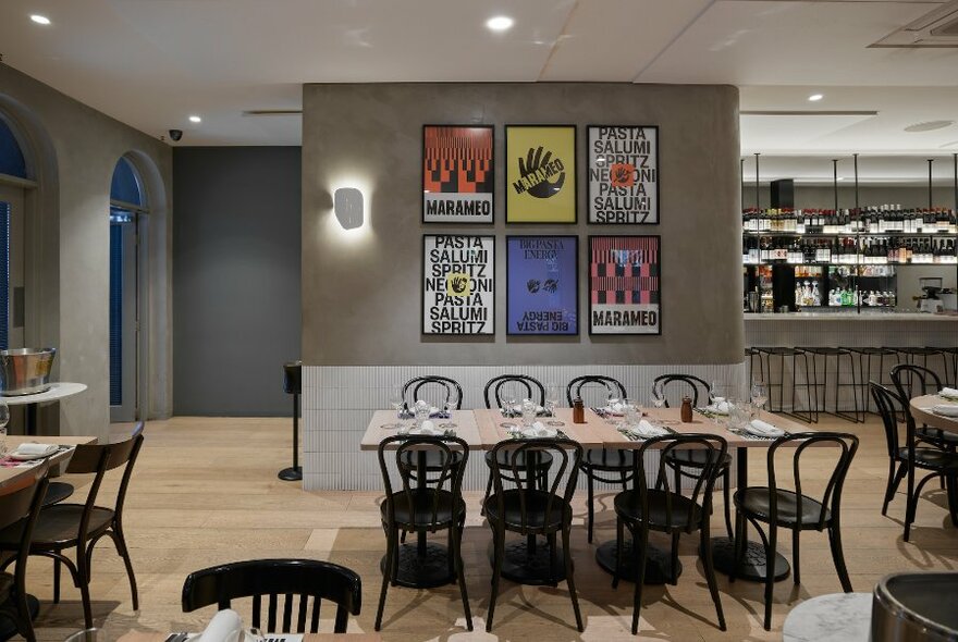 Looking at an empty restaurant dining space with bentwood chairs and colourful artwork. 