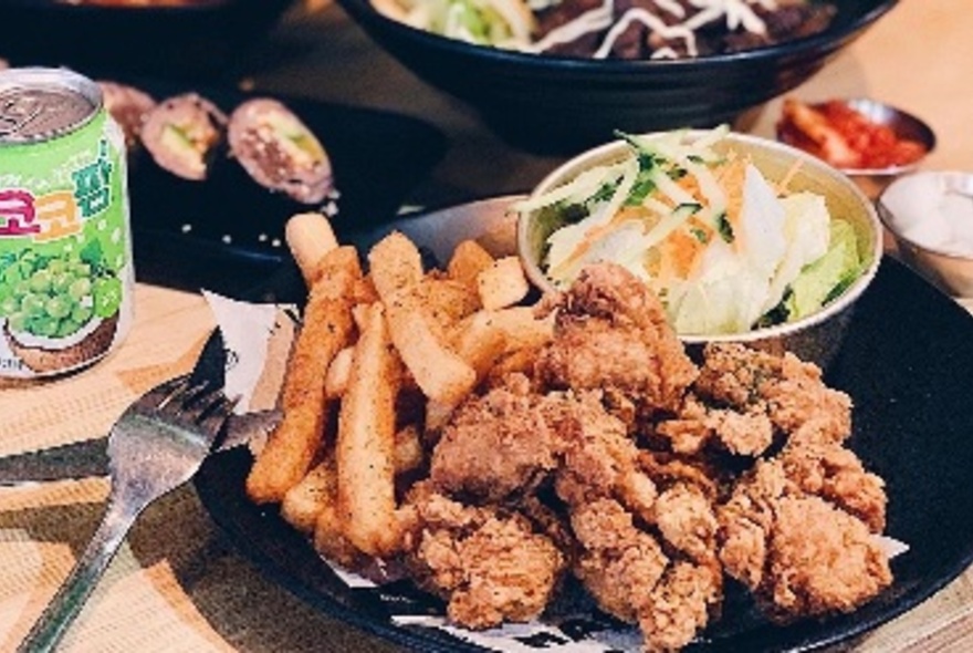 A plateful of Korean fried chicken with side dishes of salads and relishees.