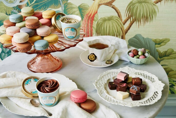 Table displaying a range of macarons and chocolates, with a chocolate mousse and a cup of tea.