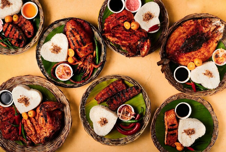 Seven plates of on a table, all with mounds of heart-shaped rice and other food arranged on them.