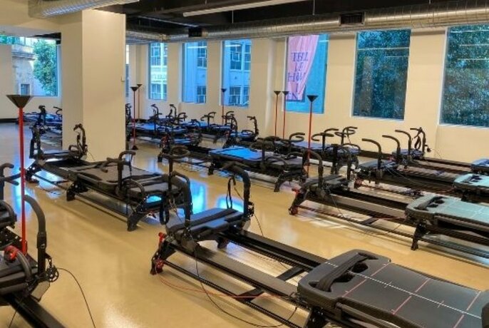 Rows of megaformer machines in a fitness studio. 