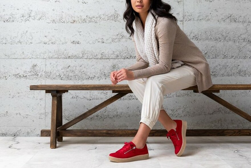 Woman wearing bright res casual shoes.