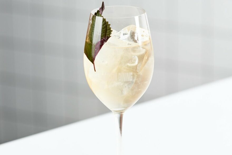 White beverage in a wine glass filled with ice.