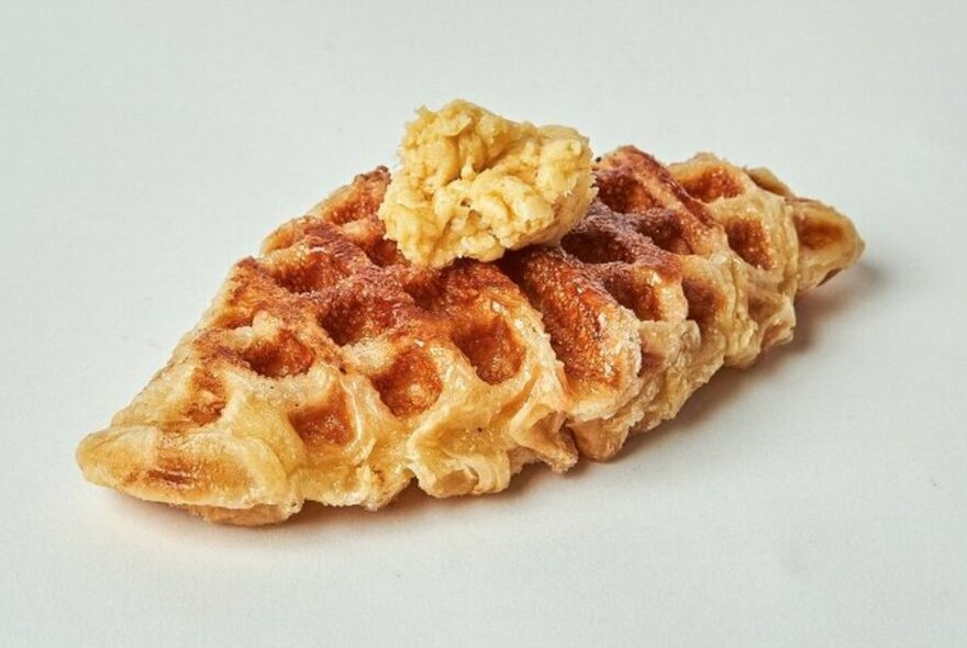 A croffle, a cross between a waffle and a croissant, dusted with cinnamon and a knob of butter.