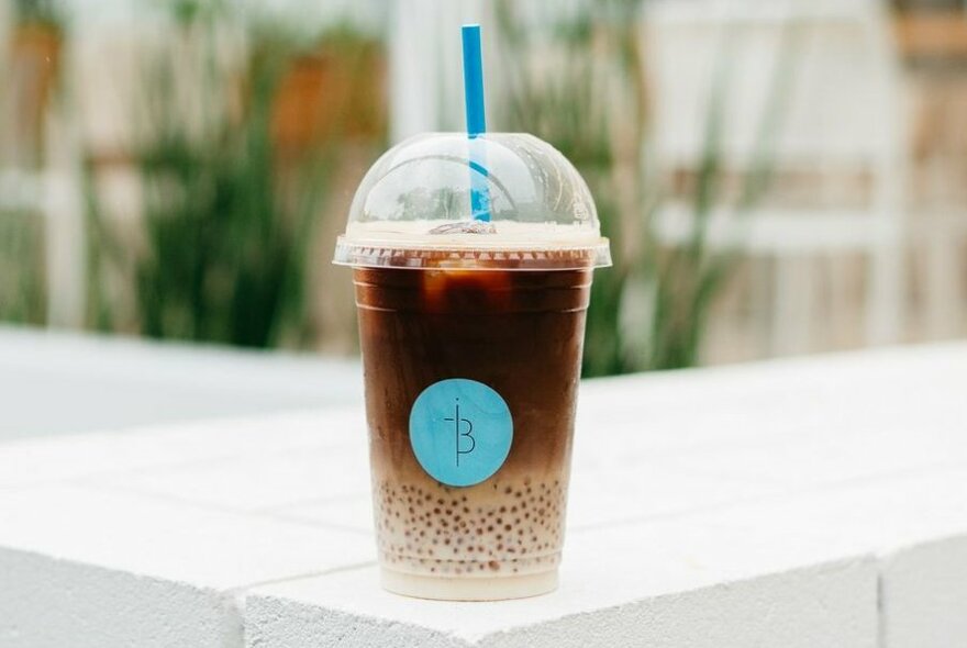 A coffee with boba in a takeaway cup