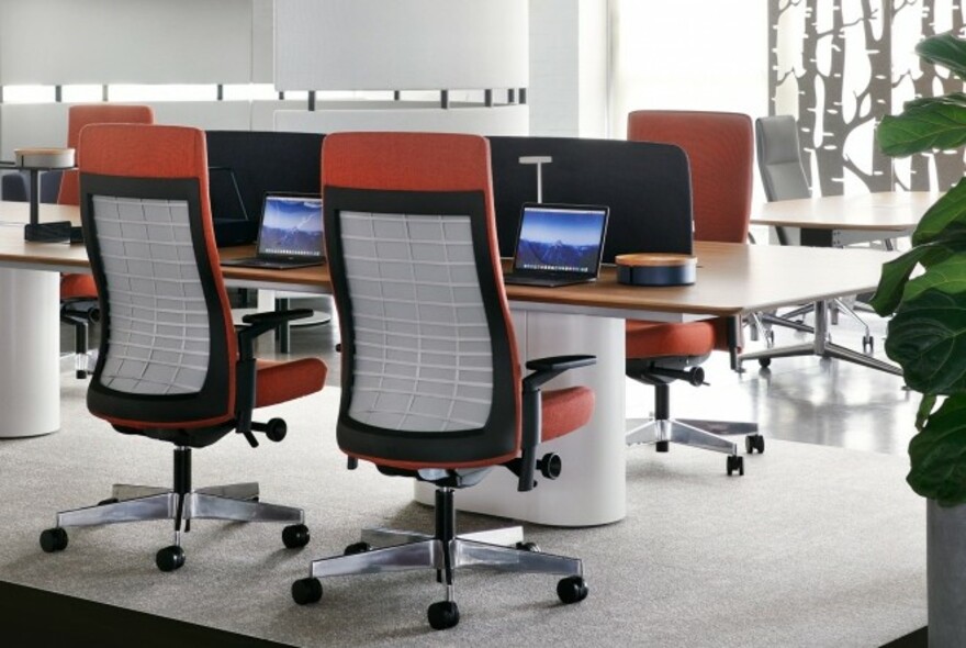 Stylish desks and orange office chairs on rollers.