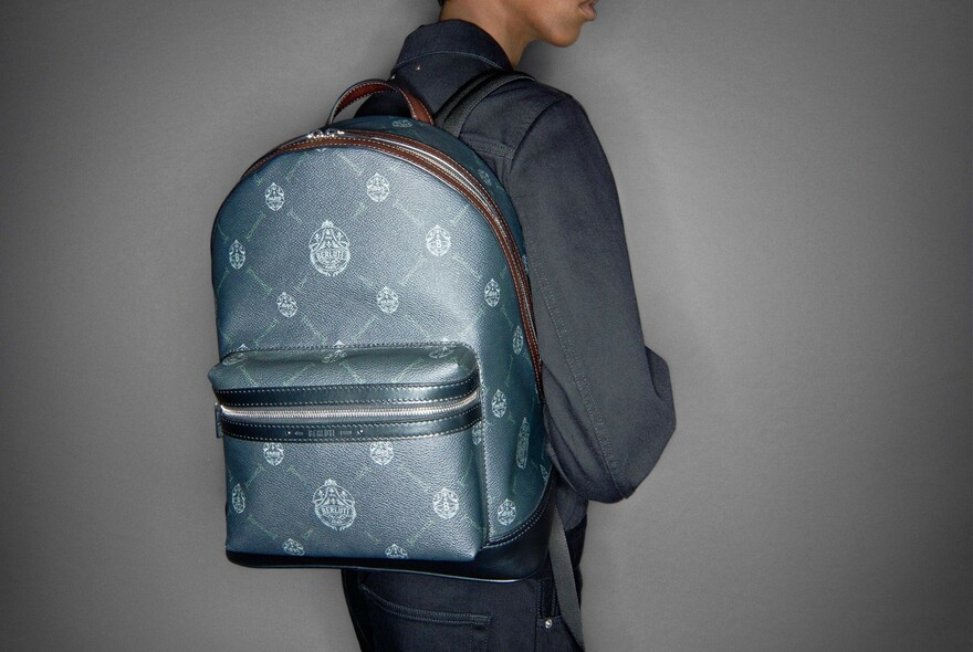 Model wearing a grey backpack with logo pattern.