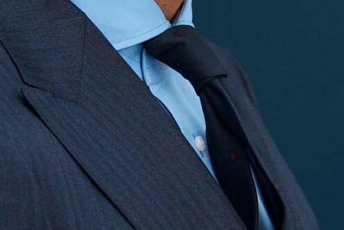 Close up, side view of dark blue suit and tie, light blue shirt.