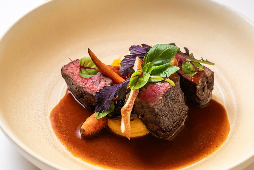 A delicious-looking rare beef dish with a brown sauce and root vegetables.