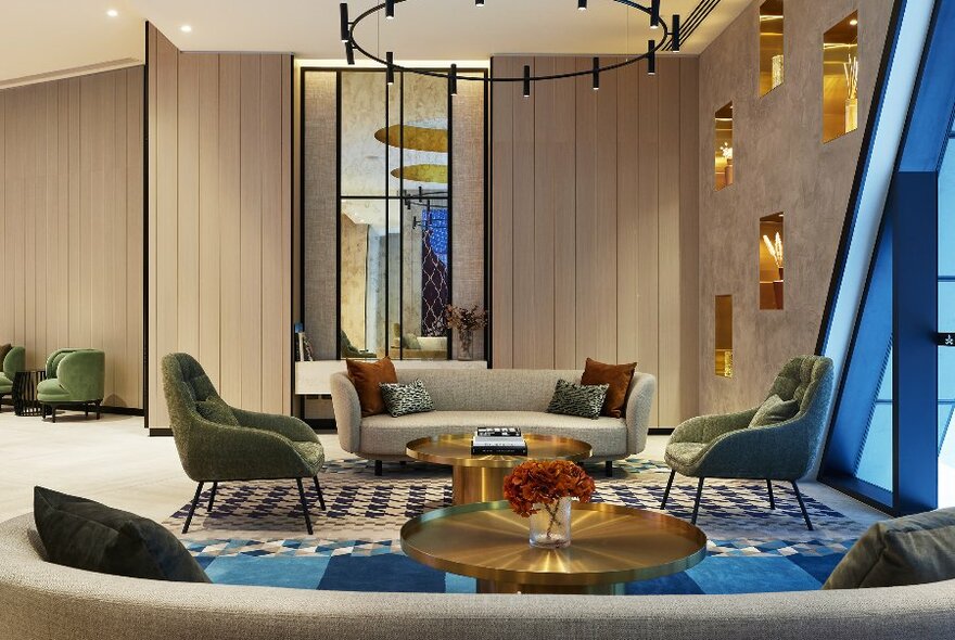A stylish hotel lobby with couches, mirrors and blue and gold accents.
