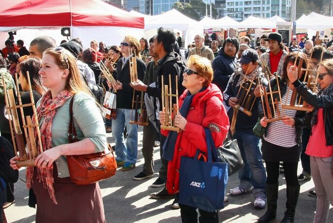 A crowd of people outdoors holding wooden objects.