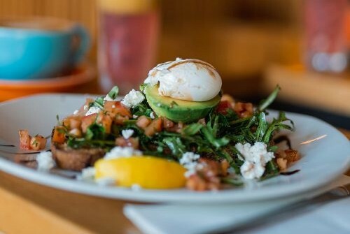 Breakfast dish of poached egg and avocado on toast.