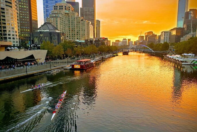 People rowing a rowboat on the Yarra River in Melbourne CBD.