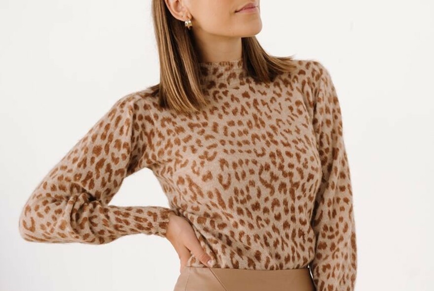 Model posing with hand on hip, wearing a leopard-print blouse.