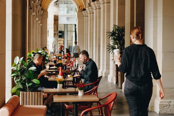 People seated at cafe tables under the covered arcades of the GPO.