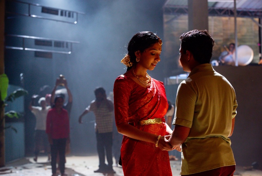 Dancers, one wearing a sari, on a dark dance floor.
