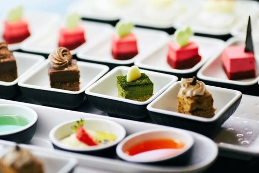 Rows of brightly coloured desserts in small individual bowls.