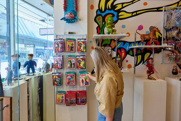 Woman looking at products hanging on the wall of a toy store.