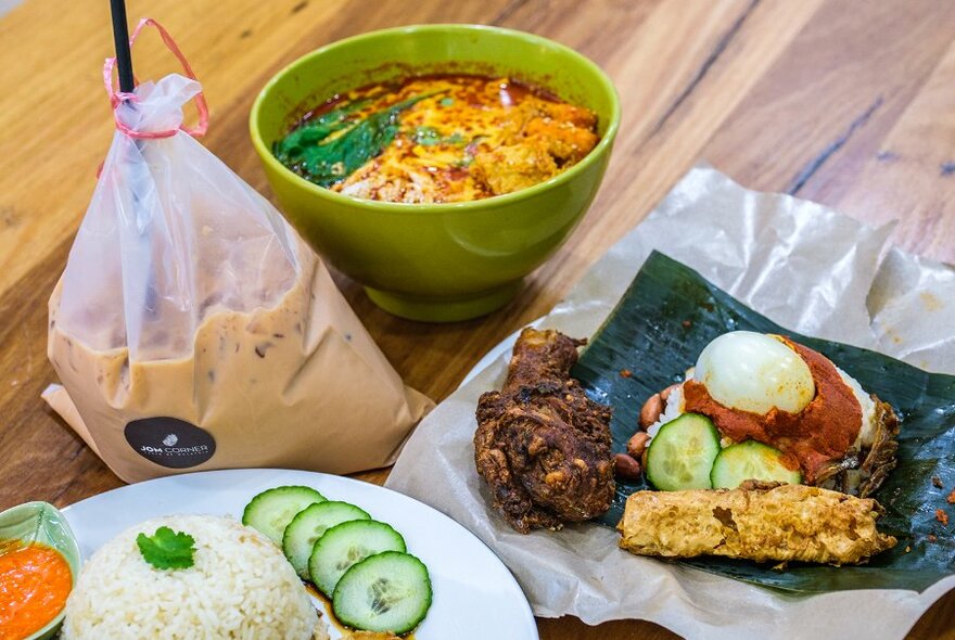 A selection of Malaysian restaurant dishes including laksa and coffee in a plastic bag.