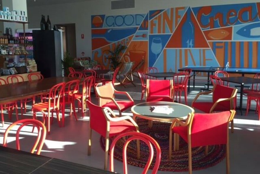 Cafe interior with red seating and tables, and blue and orange mural.