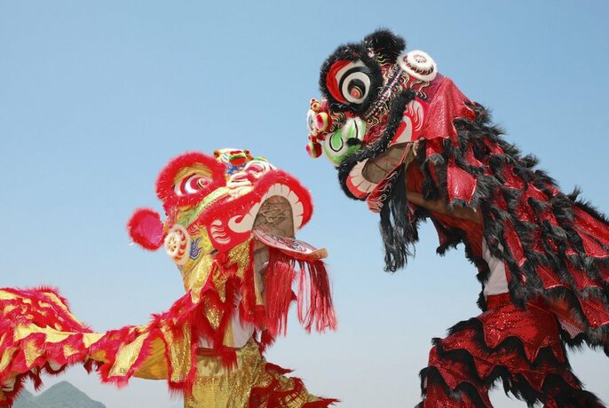 Two Chinese dragons seen from below against blue sky.