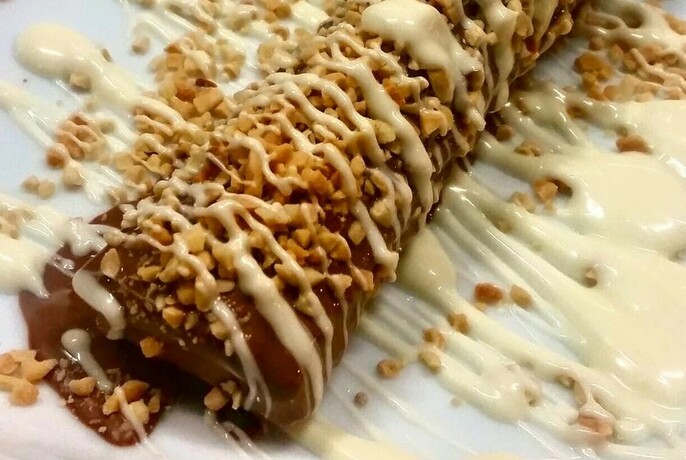 Churro Spanish doughnut sprinkled with chopped nuts.