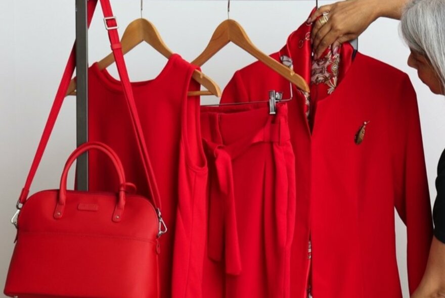 Red jacket, bag and dress on hangers.